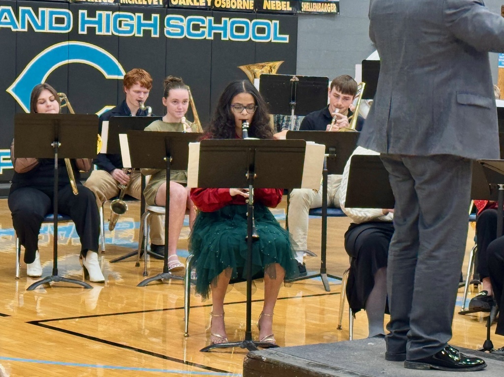 The image shows the woodwind section of the band playing from music on a music stand.