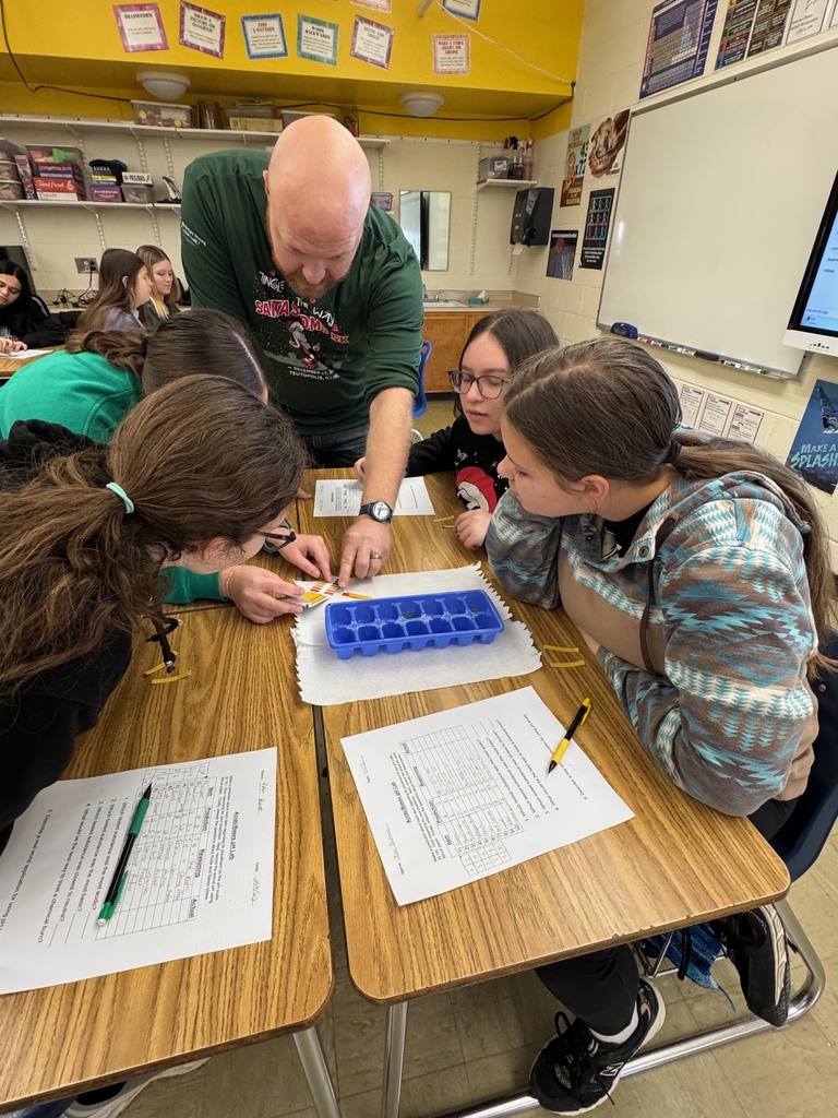 The teacher is explaining to a group of four how to read the pH chart and decide what number their color represents. 