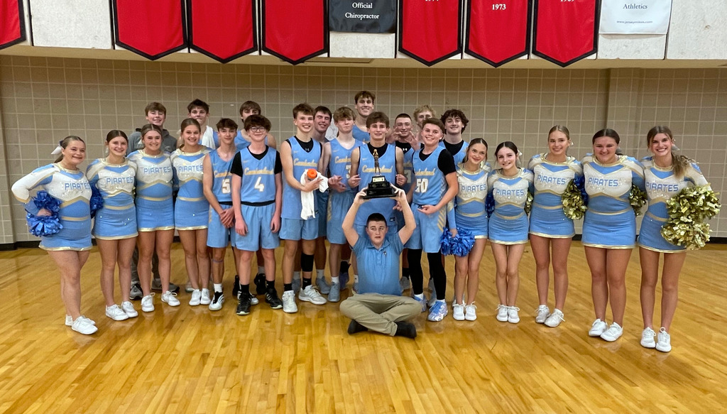 Pictured is teh boys varsity basketball team, the cheerleaders, and the manager, who is holding hte trophy above his head.