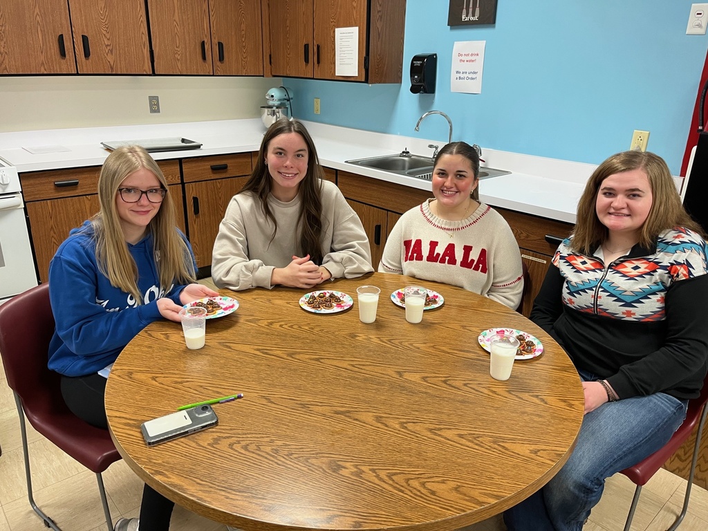 Students are at the table with their batch of holiday pretzels. The pretzels have a hershey's kiss and m&m on top.