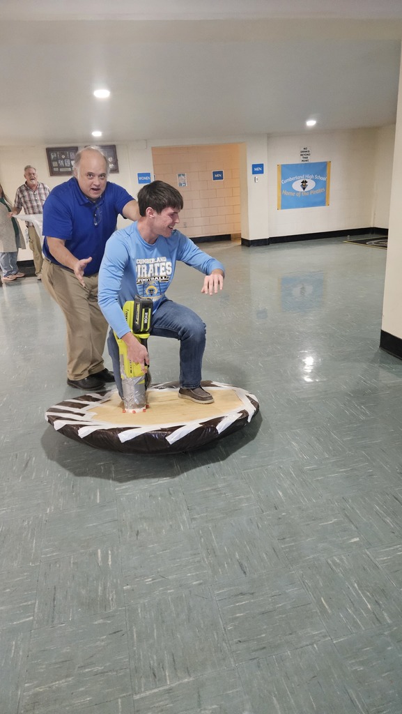 A student is riding the hovercraft. A persopn is standing in the back for support.