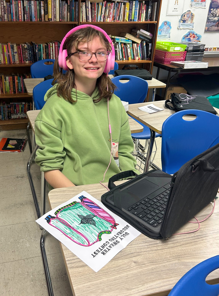 A student is sitting at her desk designing her sweater to look like the green amd red designs.