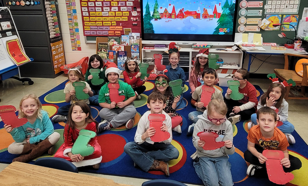 The class is sitting on the carpet and holding theirstockings.