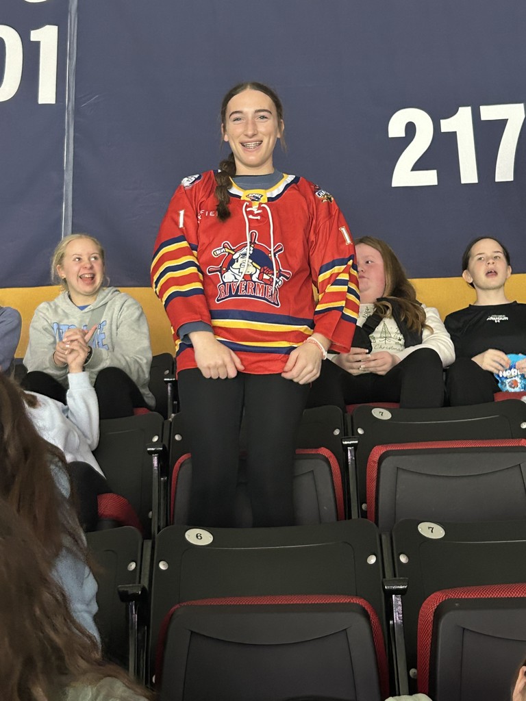 A student is standing. She is wearing a Rivermen jearsy. 
