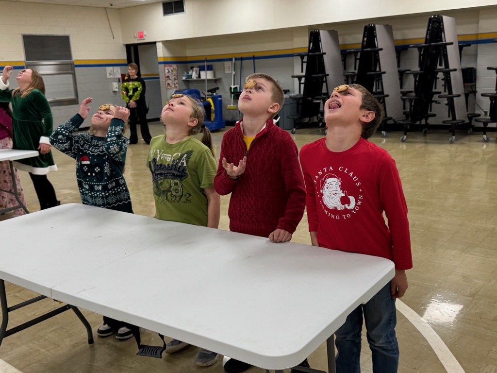 Students have a cookie on their face that they are trying to get to their mouths without the use of their hands. 