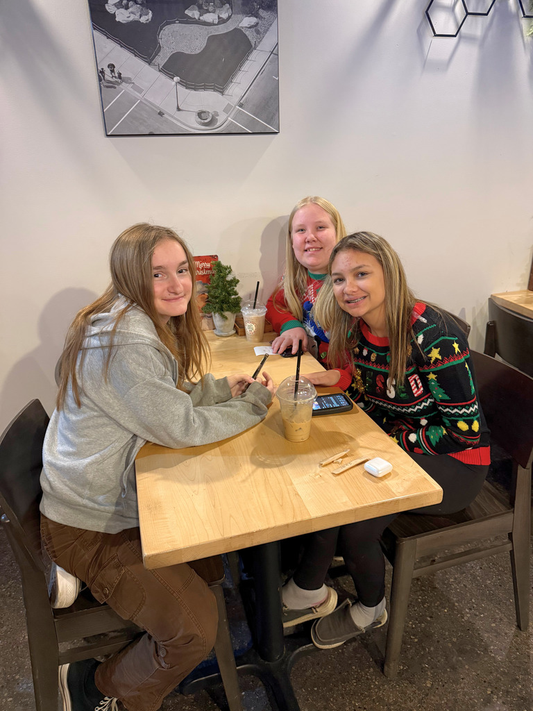 Students are sitting at table in a restaurant waiting for their food. 