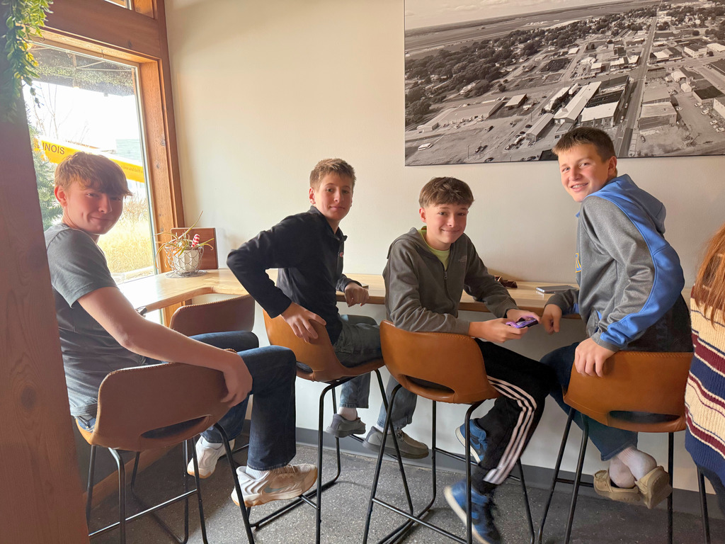 Students are sitting at table in a restaurant waiting for their food. 