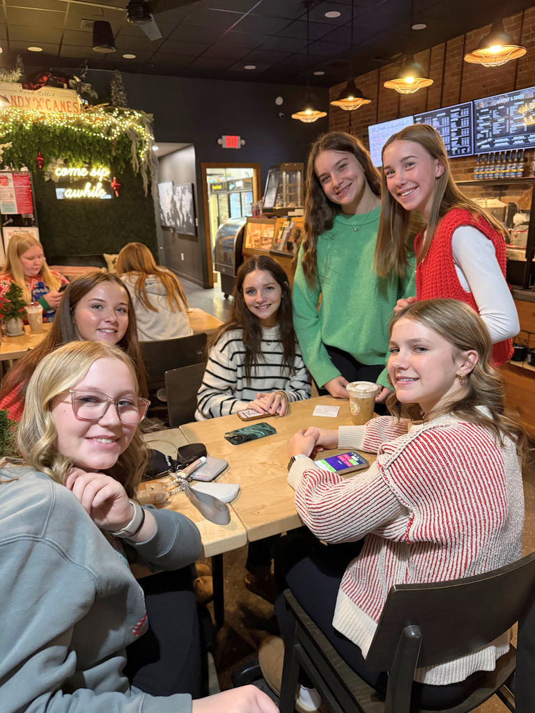 Students are sitting at table in a restaurant waiting for their food. 