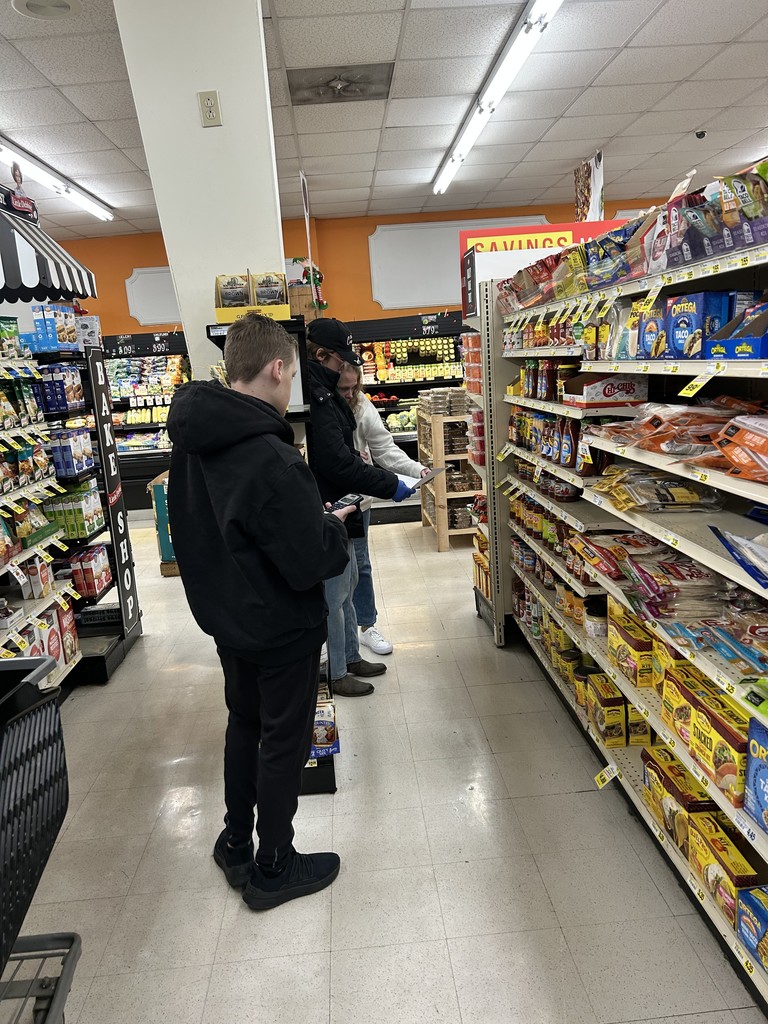 A student is using a calculator to price items on a shelf. 