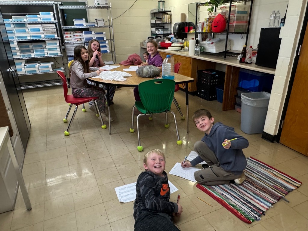 Students are happily working on a project on the floor and tables. 