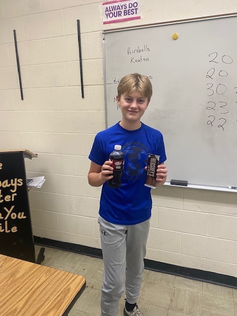 The winner of the tournament is holding a soda and candy bar. 