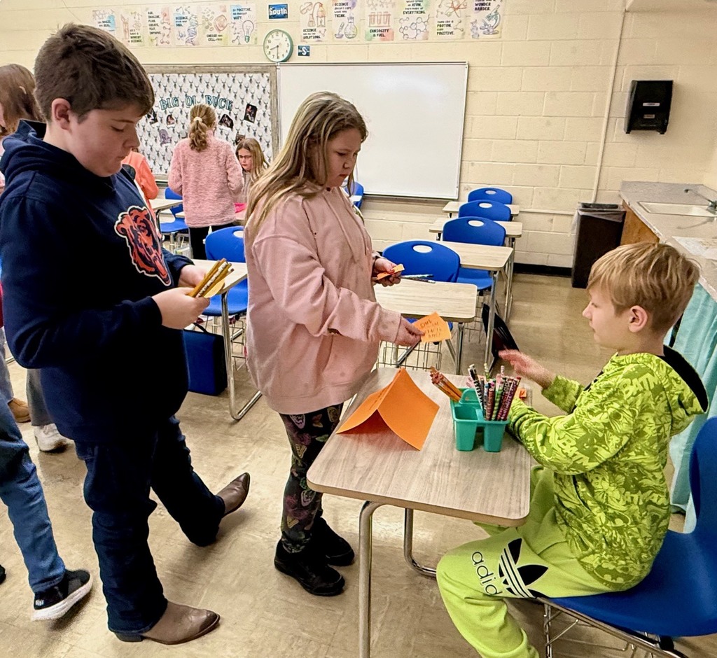 A student is at another student's desk buying a pencil. Other students are looking on.