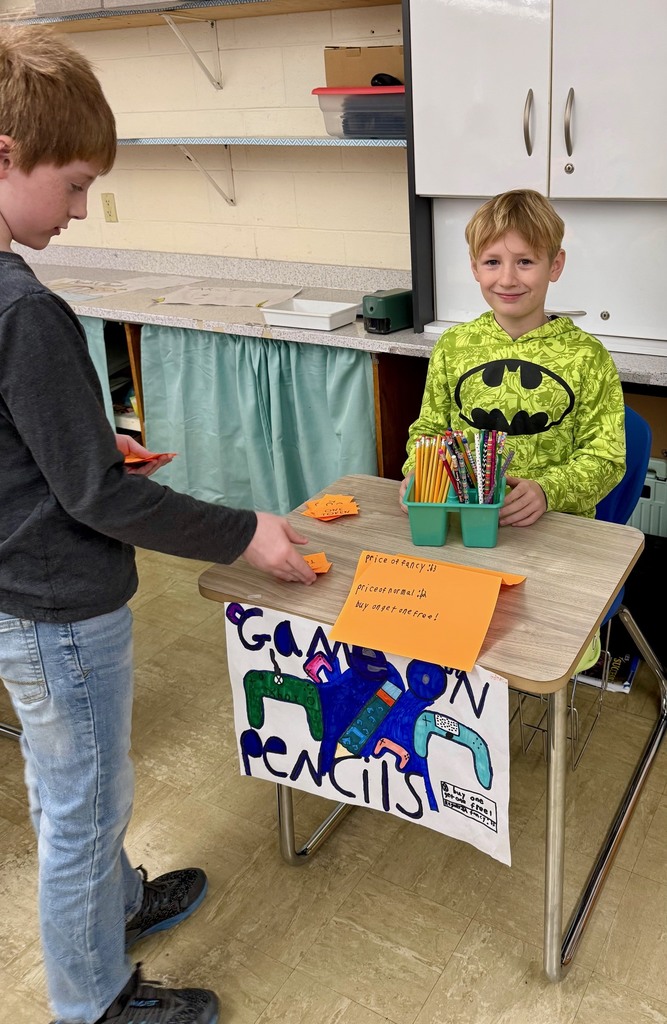A student is at another student's desk buying a pencil.