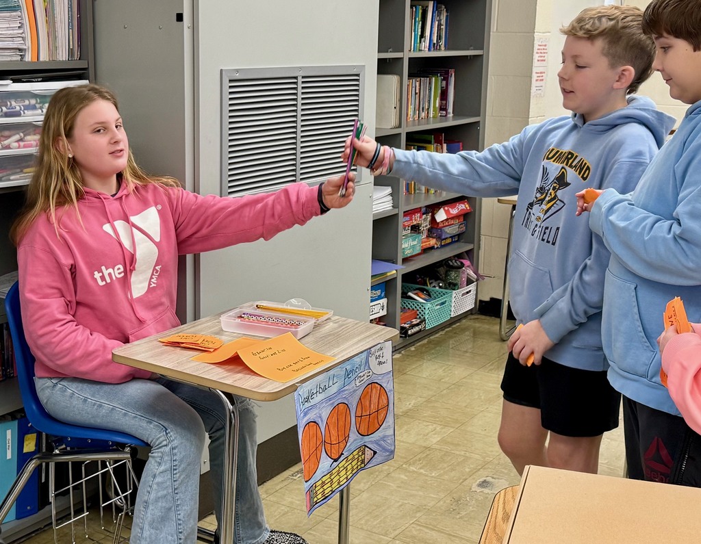 A student is at another student's desk buying a pencil.