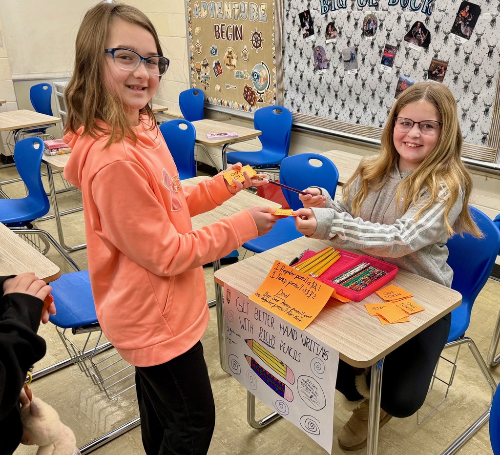 A student is at another student's desk buying a pencil.