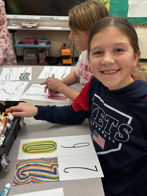 Students are creating line art. They are drawing lines around the numbers 2026.