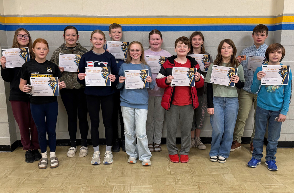 Students are in a group against the wall. They are holding up their perfect attendance certificates. 