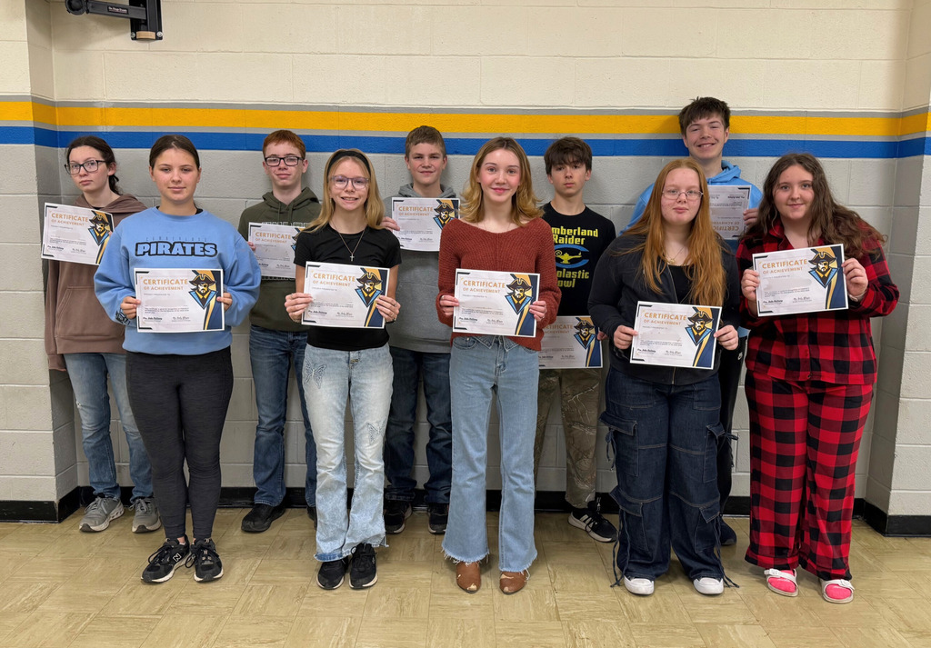 Students are in a group against the wall. They are holding up their perfect attendance certificates. 