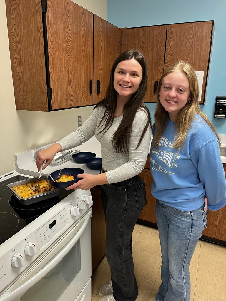 Students are creating their own pizzas. The students are dishing a bowl of caserole. 