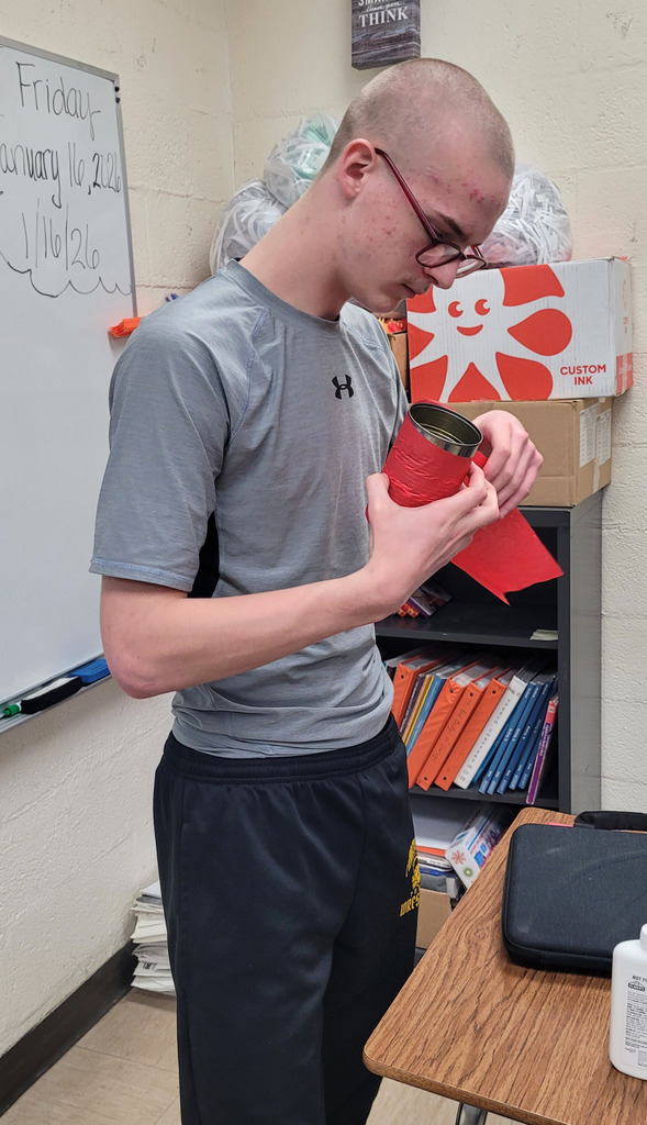 A student is making a phone prototype. It is a can with string attached. 