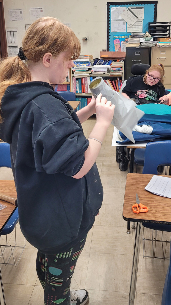 A student is making a phone prototype. It is a can with string attached. 