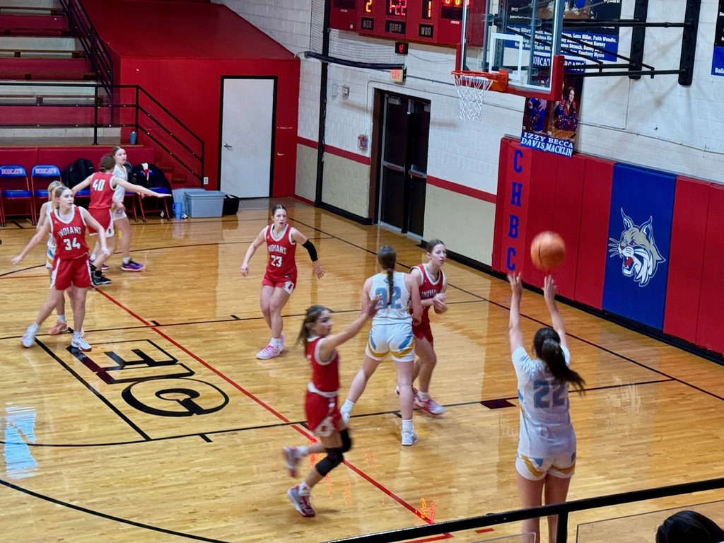 The game is in progress. The home team, Cumberland, has a girl shooting a three point shot from the right side. 