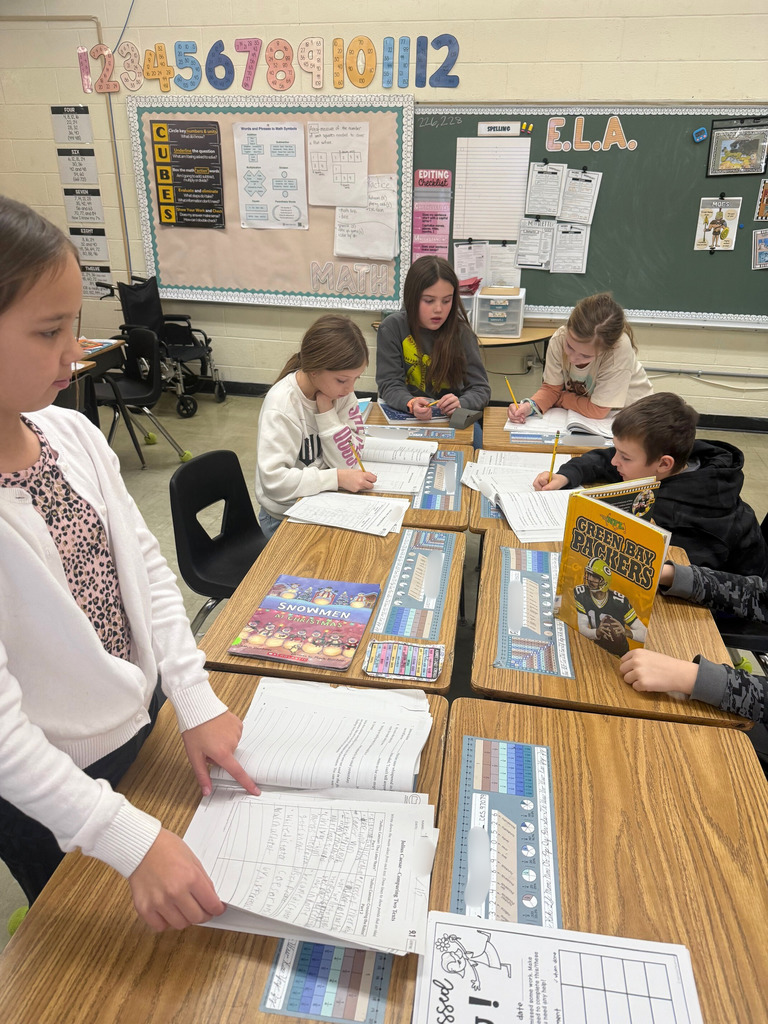 Students are sitting at their desks. They are filling out a form, adding details about Julius Caesar being a traitor and a hero. 