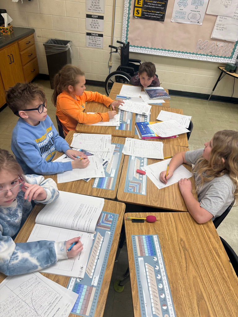 Students are sitting at their desks. They are filling out a form, adding details about Julius Caesar being a traitor and a hero. 