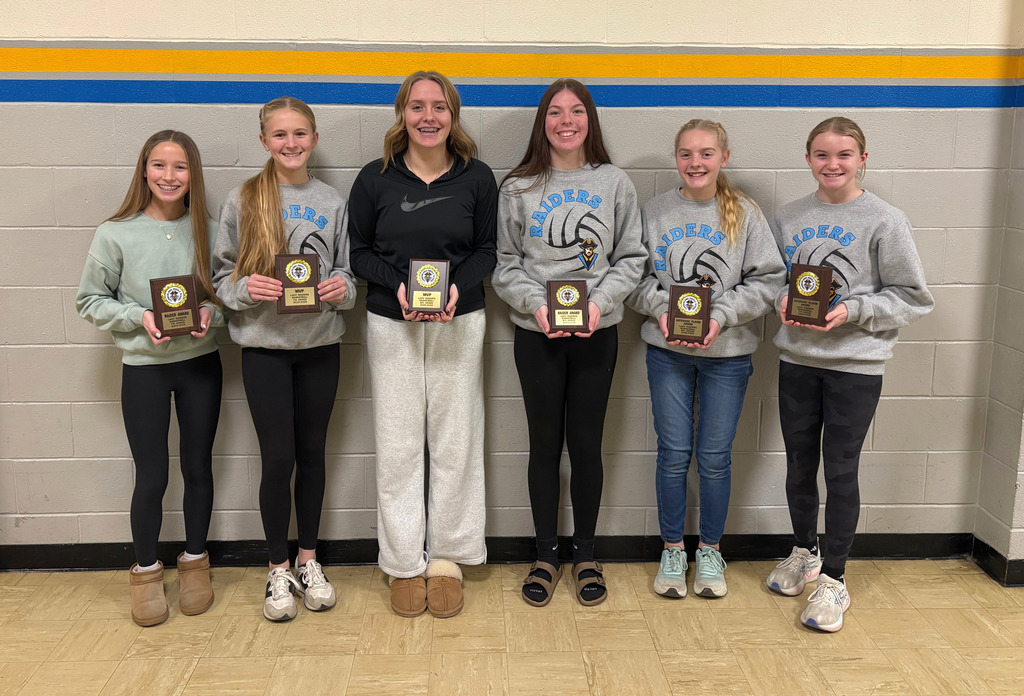 Pictured are the six award winners, each holding their plaque, and standing against the grey wall. 