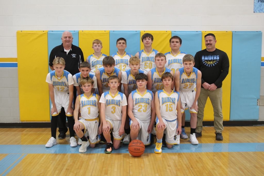 Pictured is the 8th grade basketball team. There are three rows of boys in white uniforms. There is one coach on each side of the team. 