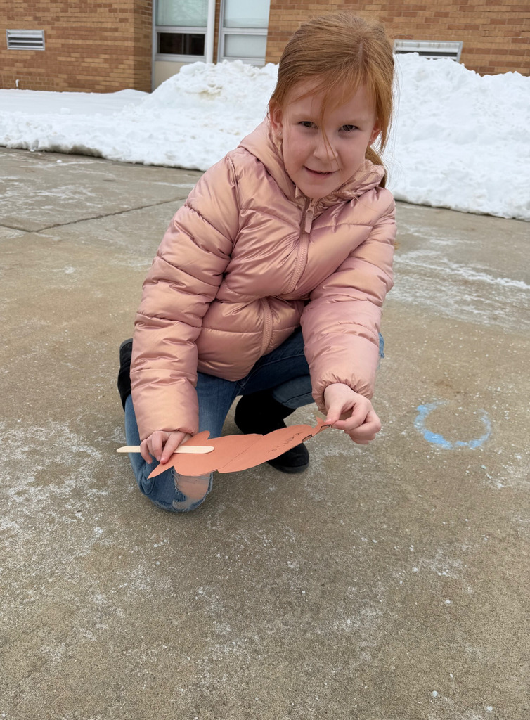 A student is holding a groundhog puppet to the ground to see if a shadow can be seen. 