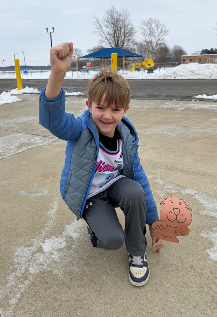 A student is holding a groundhog puppet to the ground to see if a shadow can be seen. 