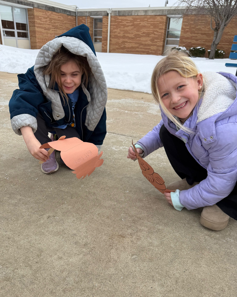 A student is holding a groundhog puppet to the ground to see if a shadow can be seen. 