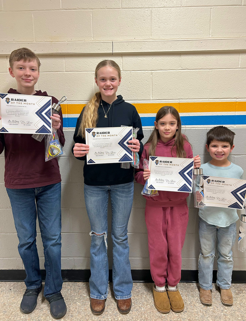 Four students are standing against the wall. Each is holding a certificate, goodie bag, and water bottle. 