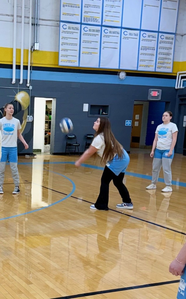 A student is bumping the volleyball over the net to the opposite side of the court. 