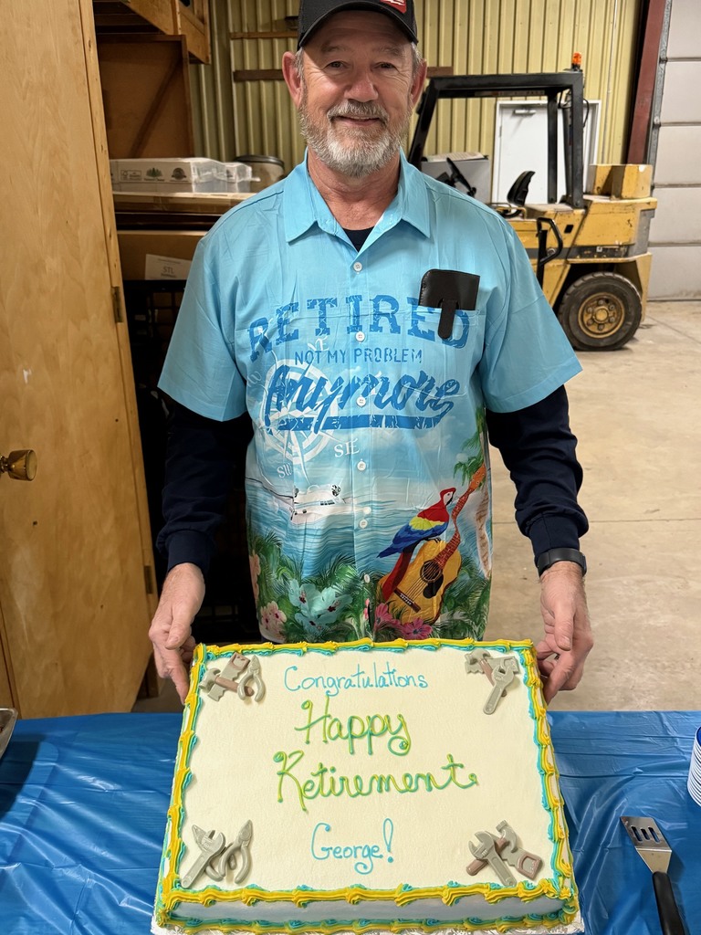 Pictured is GH holding his retirement cake. The cake says Congratuations, Happy Retirement, George! There are fondont tools in the corners. 