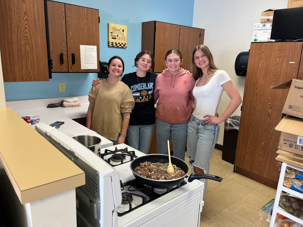Pictured are one group of winners. They are standing beside a stove with a pan of meat and vegetables.