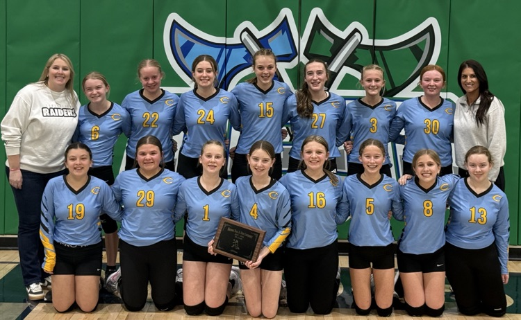 The team is in two rows flanked by the two coaches. Two girls are holding the plaque  