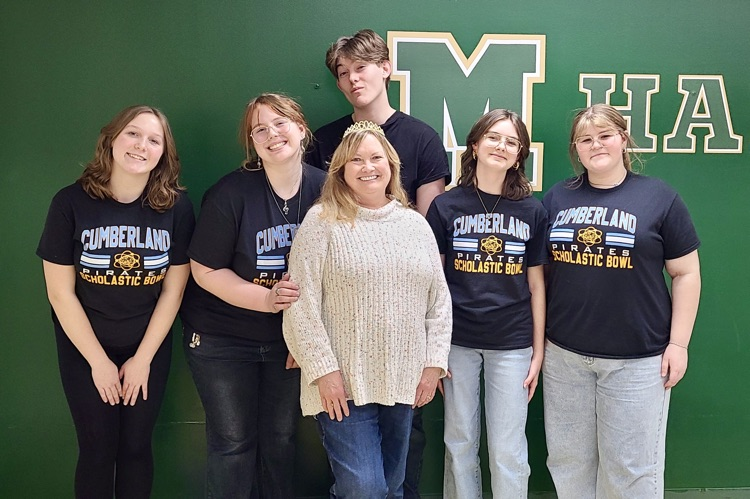 The team standing behind their coach. the coach is wearing a crown  