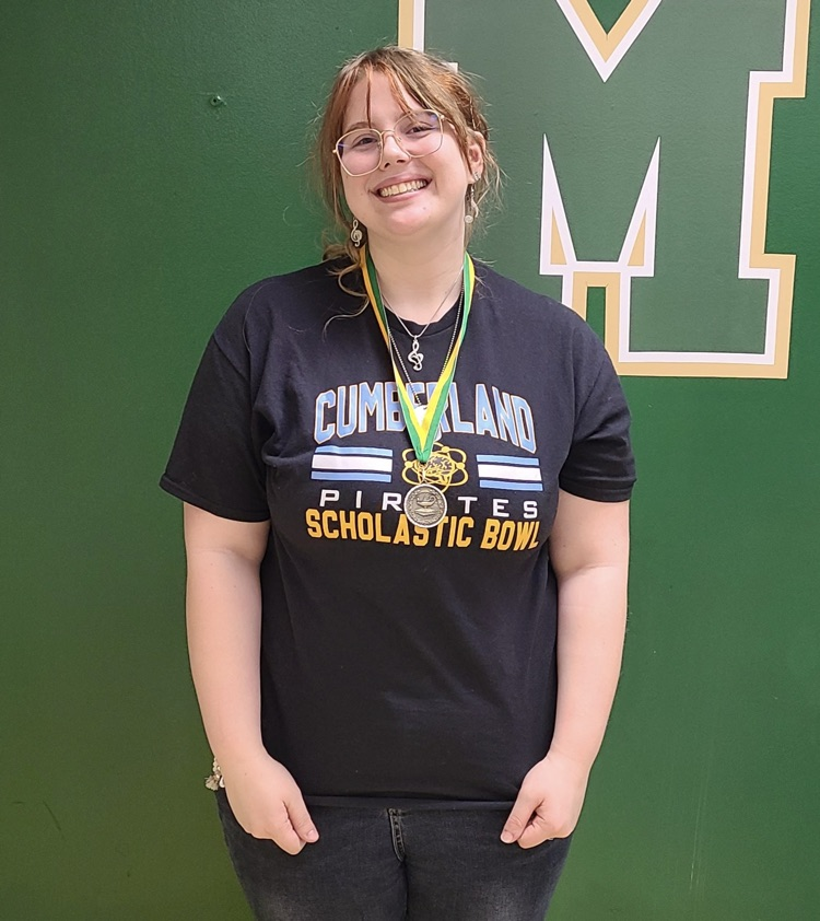 AJ is standing in front of a green wall. she is wearing her all-tournament medal  
