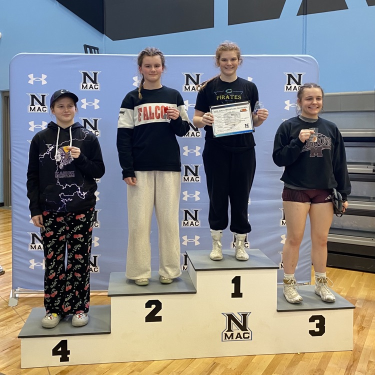 NB is standing atop of the podium. she is holding the brackets of her class