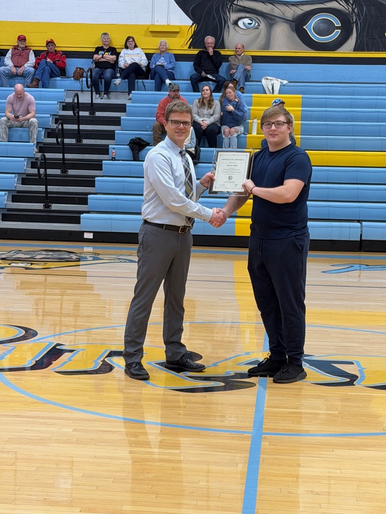 Pictured is DO accepting the certificate from Mr. Huffman, Principal, at center court. They are shaking hands and holding the certificate. 