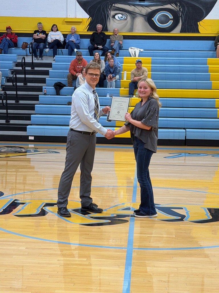 Pictured is ES accepting the certificate from Mr. Huffman, Principal, at center court. They are shaking hands and holding the certificate. 