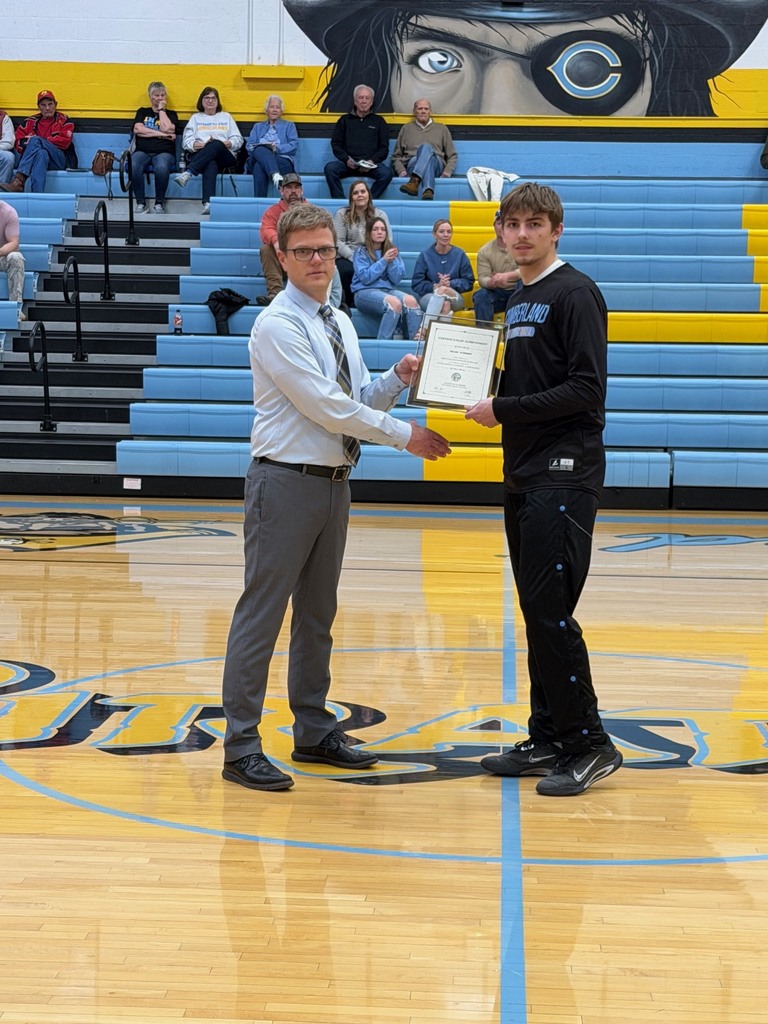 Pictured is KB accepting the certificate from Mr. Huffman, Principal, at center court. They are shaking hands and holding the certificate. 