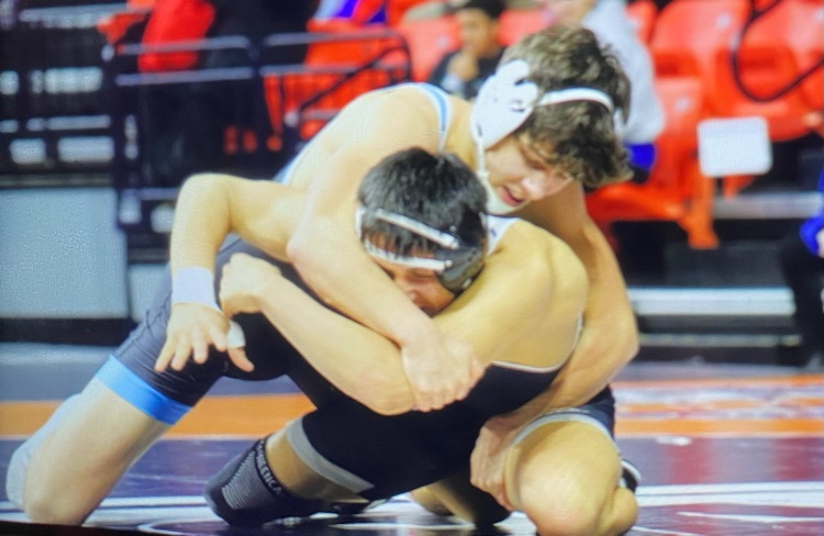 The opponent is on his knees. OM is wrapped around his back, moving him to the ground.