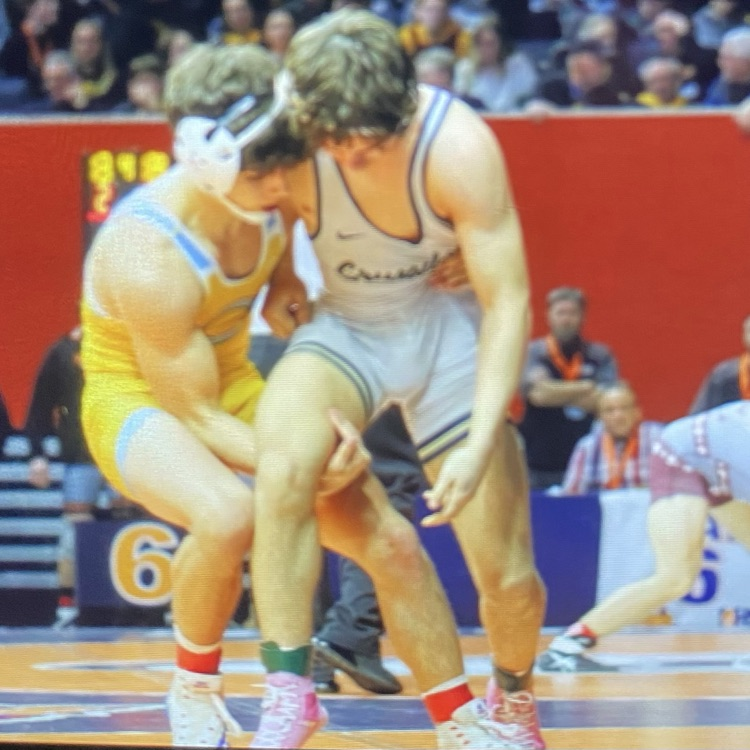 Owen and his opponent are standing. Owen has his hand around the opponents back and under his leg.