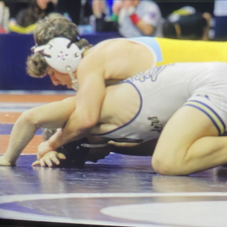 Owen is laying on top of his opponent. His opponent is faced down. Owen’s arms are pulling the opponents arms back in order to pin him.