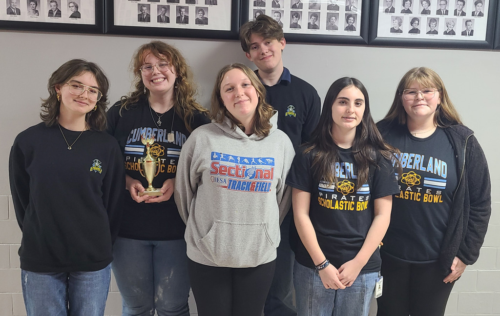 Pictured is the JV team. There are six members standing side by side. The second member is holding the trophy.