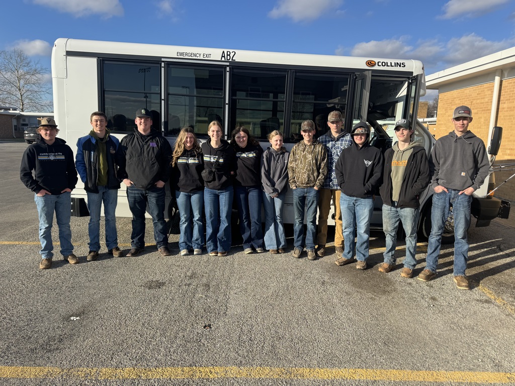 Pictured is the team of 12 standing side by side in front of the white school bus.
