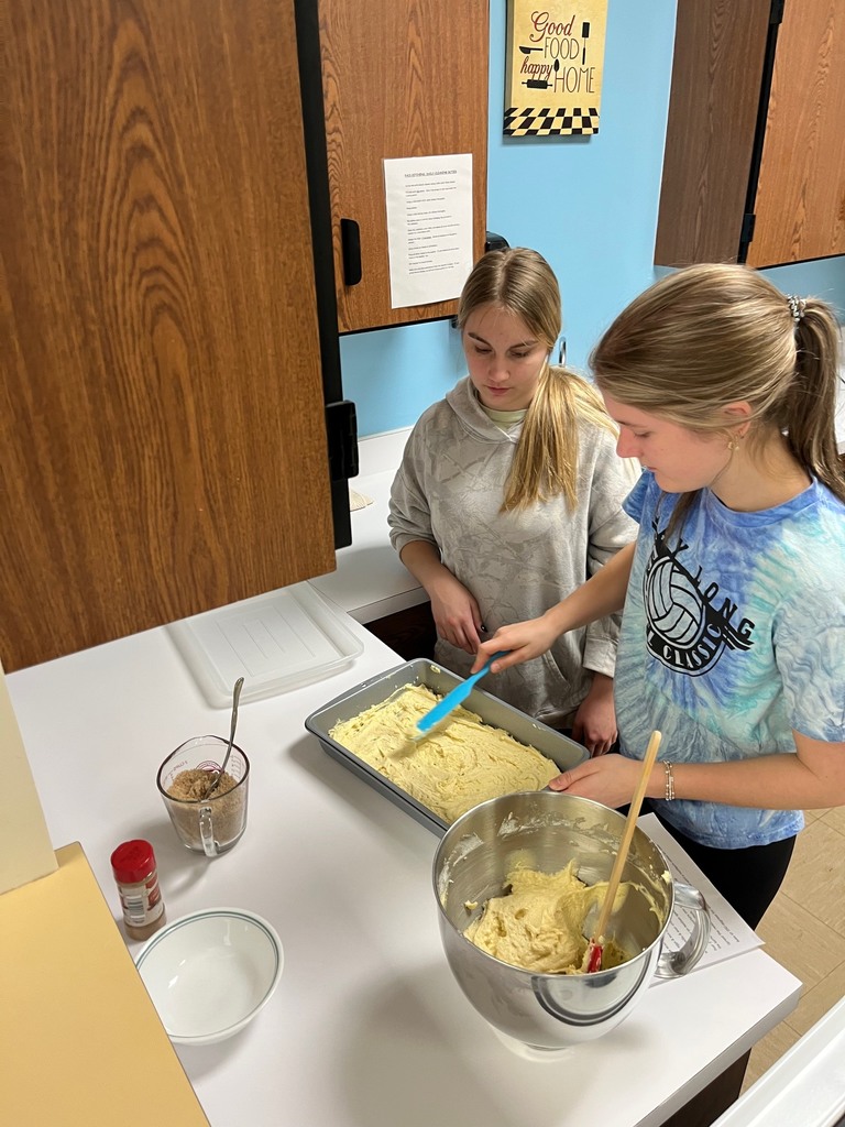 Two students are spreading the batter into a pan. One student is smoothening it with a knife.
